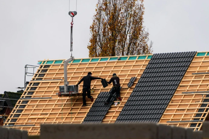 Des ouvriers du bâtiment installant des tuiles de toit sur un nouveau bâtiment
